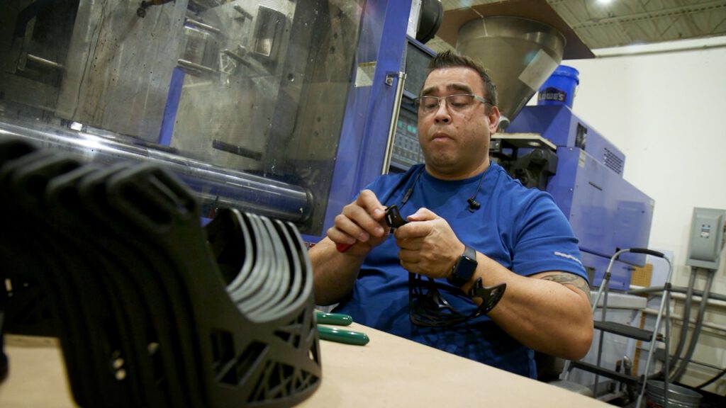 A technician inspects custom plastic parts as they come out of the mold at a product development firm.