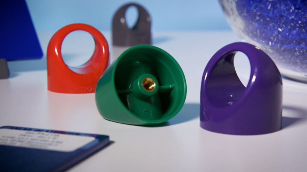 Plastic injection molded caps in a variety of colors sit together on a table.