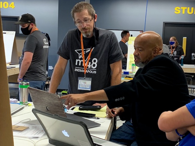 An Industrial Designer looks over the plans for a prototype with a Make48 contestant.